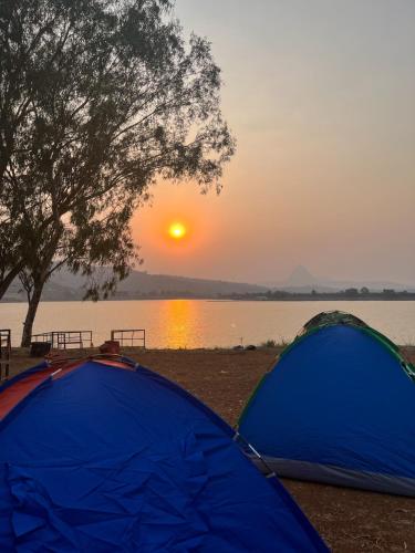 two tents on the shore of a lake at sunset at Swarg Resort in Pune