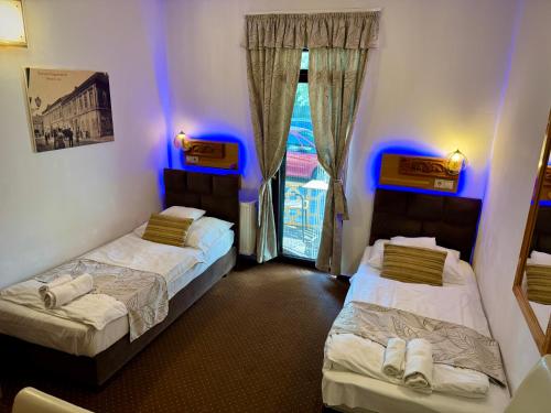 two beds in a room with blue lights at Fészek Fogadó - Pension Nest in Mosonmagyaróvár