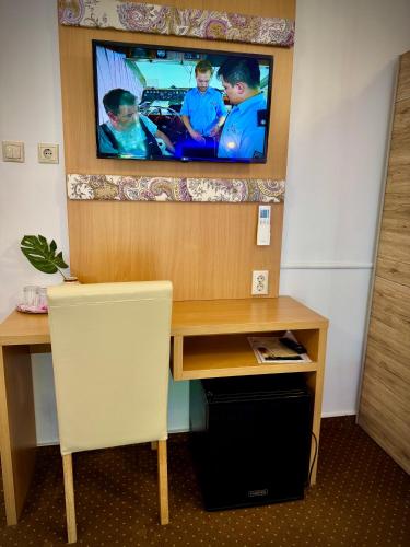 a room with a desk with a tv on the wall at Fészek Fogadó - Pension Nest in Mosonmagyaróvár