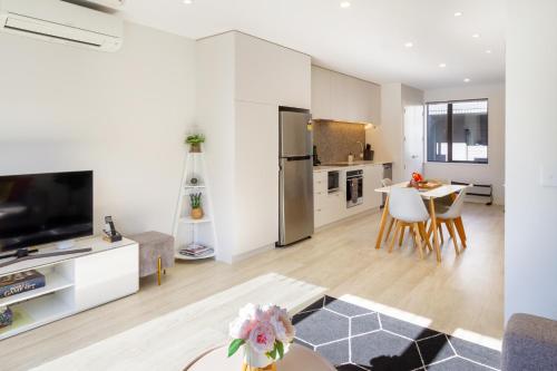 a white living room with a table and a kitchen at Stadium Edge Retreat Modern 2-Bed plus Carpark in Christchurch