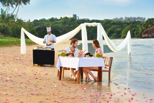 a group of people sitting at a table on the beach at Mandara Resort Mirissa in Mirissa