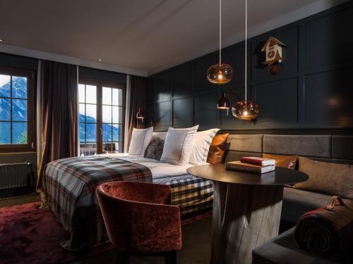 a bedroom with a bed and a table and a couch at HUUS Gstaad in Gstaad