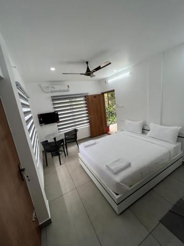 a white bedroom with a bed and a piano at Hotel Eleven Space Kochi in Cochin