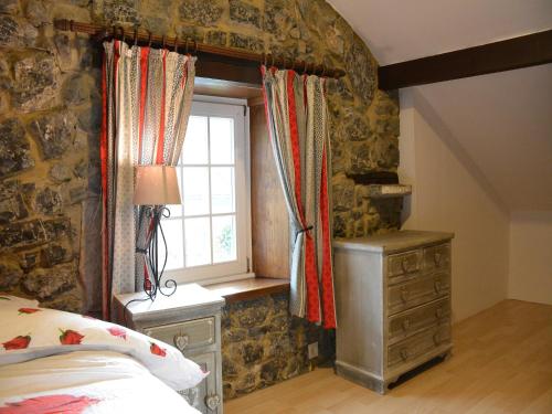 a bedroom with a stone wall and a window at Nice gite with low ceilings in Han-sur-Lesse in Han-sur-Lesse