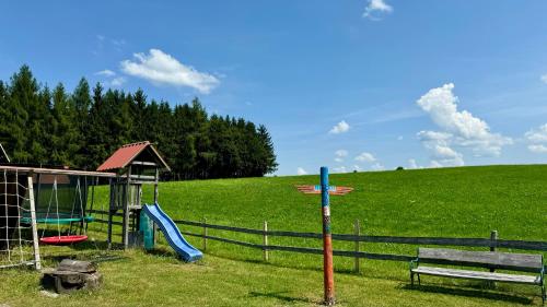 a playground with a slide and a bench in a field at See I Jacuzzi I Balkon I Parkplatz I Bio Hof I TV in Rieden am Forggensee