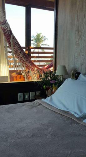 a bed in a bedroom with a hammock outside a window at Pousada dos Veleiros in Nova Almeida