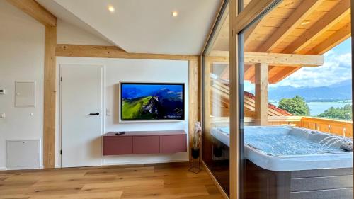 a room with a tub with a tv on the wall at See I Jacuzzi I Balkon I Parkplatz I Bio Hof I TV in Rieden am Forggensee