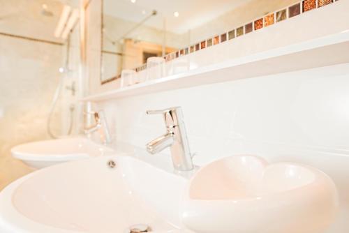 a bathroom with two sinks and a mirror at Hotel Alpenhof Kristall in Mayrhofen