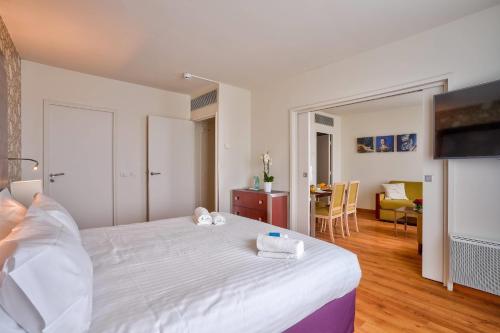 a bedroom with a large white bed and a living room at Clarion Paris CDG Airport in Roissy-en-France
