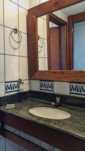a bathroom counter with a sink and a mirror at Pousada dos Veleiros in Nova Almeida
