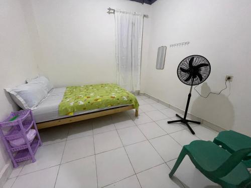 a bedroom with a bed and a fan in it at Costa Hostel in Deli