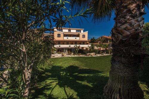 a large house with a palm tree in front of it at Hotel Raffael PHG in Putzu Idu