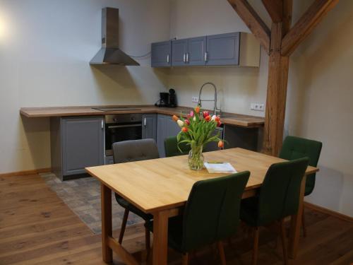a kitchen with a wooden table with a vase of flowers on it at Pension Bäumi-Hof in Seehausen