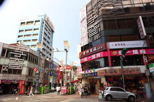 a busy city street with tall buildings and a car at E-House Xining Branch in Taipei