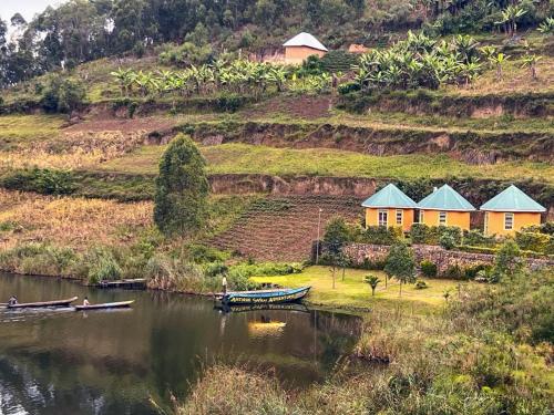 a house on a hill next to a body of water at Antique cottages in Kabale
