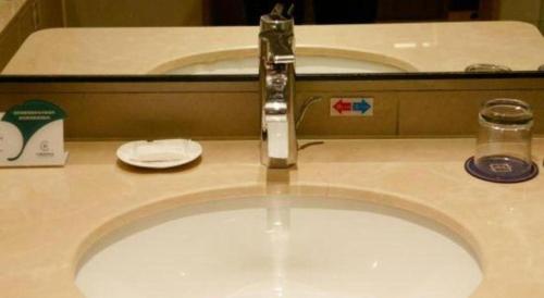 a bathroom sink with a faucet on a counter at Grand Metropark Hotel Chongqing in Chongqing