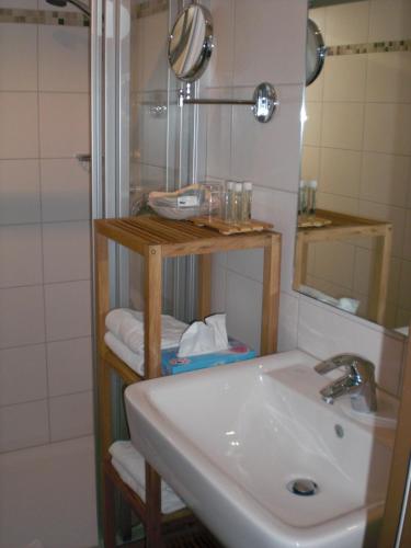 a bathroom with a sink and a mirror and a shower at Akzent Hotel Jonathan in Lippstadt