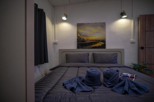 a bedroom with a bed with towels and a painting at Mama's Tree Homemade Croissant, Bed & Breakfast in Klaeng