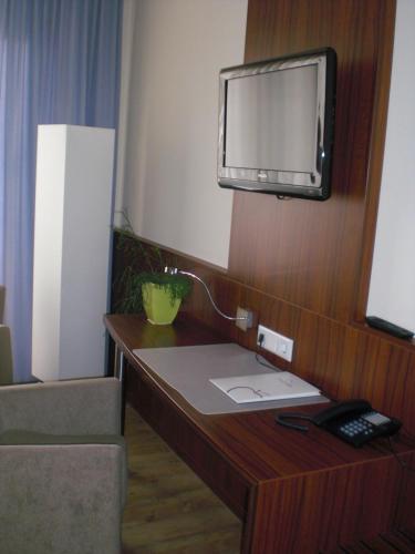 a room with a desk with a television on a wall at Akzent Hotel Jonathan in Lippstadt