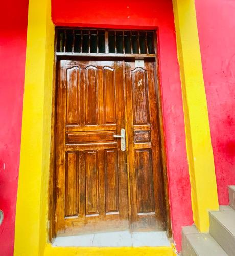 a red and yellow building with a wooden door at Costa Hostel in Deli
