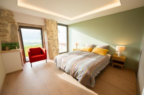 a bedroom with a bed and a red chair at Le 214, Entre Lacs et Montagnes in Les Rousses