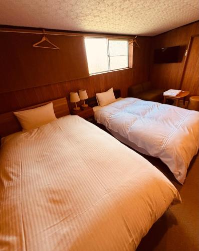 a bedroom with two beds and a window at やどバーTATSUJi in Joetsu