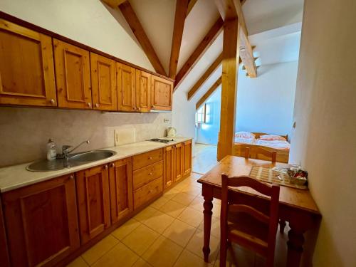 a kitchen with wooden cabinets and a sink and a table at Hotelový a jezdecký areál Dvůr Krutěnice in Krutěnice