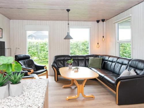 a living room with a black leather couch and a table at Luxury Retreat in Pot Strandby - By Traum Ferienwohnungen in Sønderby