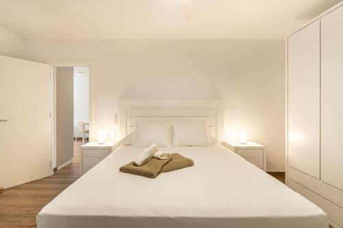 a white bedroom with a white bed with two tables at Panarea Chaparal in Costa Del Silencio
