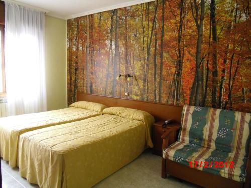 1 dormitorio con 1 cama y un mural de bosque en la pared en Hotel Noray, en San Vicente de la Barquera