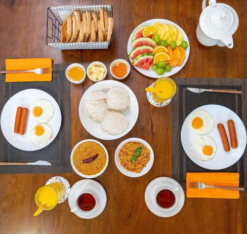 een tafel met borden met ontbijtproducten en drankjes bij Village Headman's Bungalow in Bentota