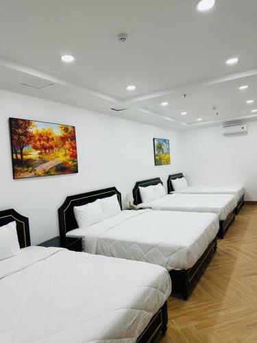 three beds in a room with white walls at khách sạn yên châu 2 in Chau Doc