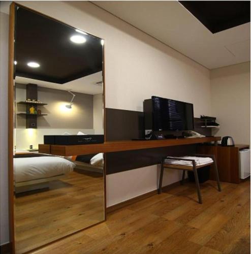 a mirror in a bedroom with a bed and a desk at KT&G Sangsangmadang Chuncheon Stay (Korea Quality) in Chuncheon