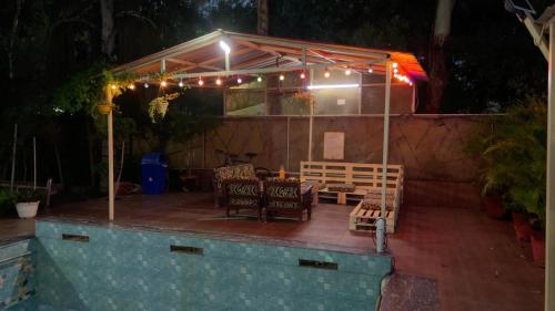 a patio with a table and chairs and lights at Amritvan Farms in Noida