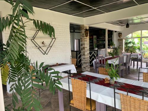 a restaurant with white tables and chairs and plants at Palm garden Resort in Gisenyi