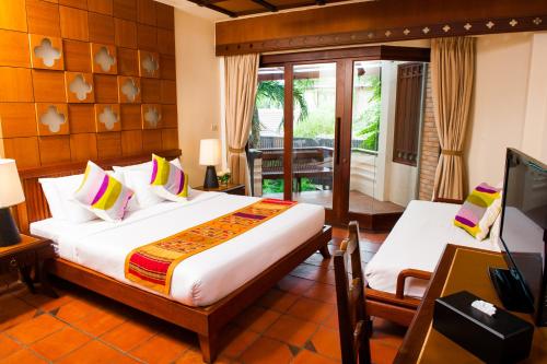 a bedroom with a bed and a television in a room at Montien House - SHA Plus in Chaweng