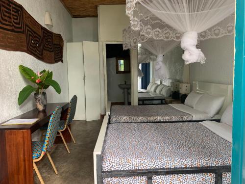 a room with two beds and a table and chairs at Palm garden Resort in Gisenyi