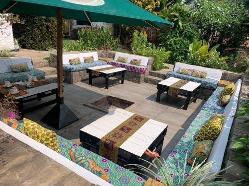 a patio with couches and tables and an umbrella at Palm garden Resort in Gisenyi