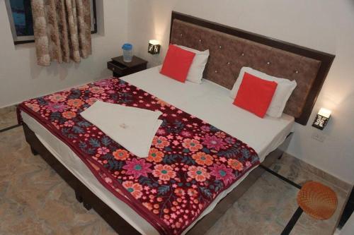 a bedroom with a bed with a flower blanket on it at Karma Hostel in Khajurāho