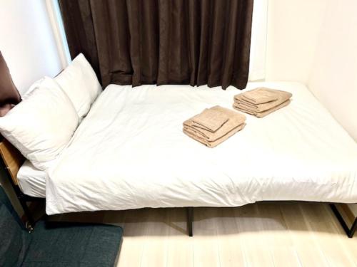a white bed with two towels on top of it at グレイシャス東新宿 東新宿駅徒歩3分 新大久保駅徒歩7分 新宿駅徒歩15分 歌舞伎町すぐ近く 美味しい韓国料理屋多数あります in Tokyo