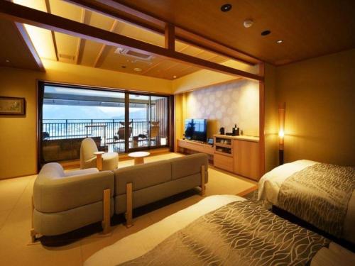 a bedroom with a bed and a couch and a television at Shiratamano Yu Kahou in Shibata