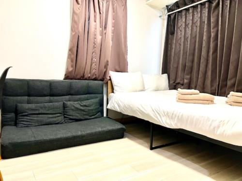 two beds and a chair in a room at グレイシャス東新宿 東新宿駅徒歩3分 新大久保駅徒歩7分 新宿駅徒歩15分 歌舞伎町すぐ近く 美味しい韓国料理屋多数あります in Tokyo