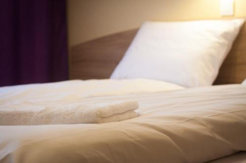 a white bed with white sheets and a pillow at Dworek nad Wisłą in Wisła