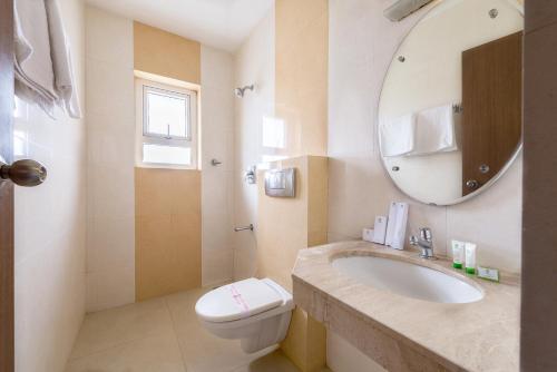 a bathroom with a sink and a toilet and a mirror at Treebo ESS Grande in Coimbatore