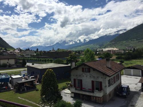 an old house in a town with mountains in the background at Le Central - Chambres d'hôte in Grône