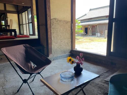 a chair and a table with a vase of flowers on it at dannouraしげの里 1棟貸切 築120年古民家 バーベキュー 海が見える in Takamatsu