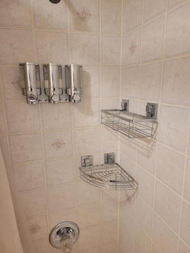 a tiled bathroom with two metal shelves on the wall at Centrally Located Southside Private Basement Suite in Lethbridge