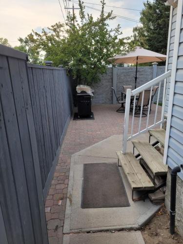 a patio with a fence and a bench and an umbrella at Centrally Located Southside Private Basement Suite in Lethbridge