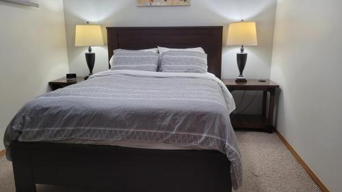 a bedroom with a bed with two lamps on two tables at Centrally Located Southside Private Basement Suite in Lethbridge
