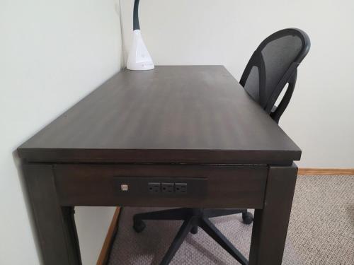 a black desk with a chair and a vase on it at Centrally Located Southside Private Basement Suite in Lethbridge